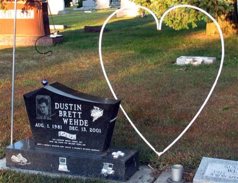 ADVANCE FOR USE SUNDAY, OCT. 23, 2011 AND THEREAFTER - This Sept. 22, 2011 photo shows the grave site for Dustin Wehde at a cemetery in Holstein, Iowa. Seen through the middle of the heart ornamentation at right is the gravestone of his father, Brett, who committed suicide at that spot the year after his son's death. In 2001, Tracey Roberts fired 9 shots from two guns into the 20-year-old neighbor who died on the floor of her bedroom. A jury will be asked to decide if she was a heroic mother who used self-defense to protect herself and her three young children from Wehde and another man who she says invaded the home, or was she a master manipulator who planned the killing and an elaborate cover story. (AP Photo/Ryan Foley)